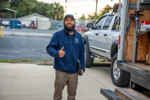 The Brothers That Just Do Gutters installer gives a smiling thumbs up next to his work truck and trailer.