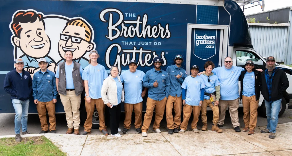 Group of The Brothers That Just Do Gutters franchise employees posing in front of a The Brothers that Just Do Gutters truck