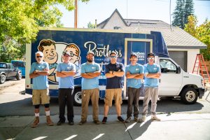 Group of The Brothers That Just Do Gutters installers stand in front of a branded work truck with their arms crossed looking professional